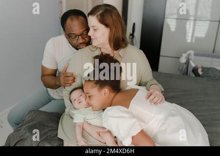 Liebevoller Vater und Mutter mit Tochter, die zu Hause ein kleines Mädchen umarmt Stockfoto