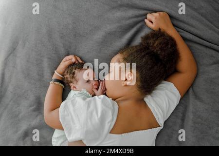 Ein Mädchen liegt im Bett mit einer süßen kleinen Schwester im Schlafzimmer zu Hause Stockfoto