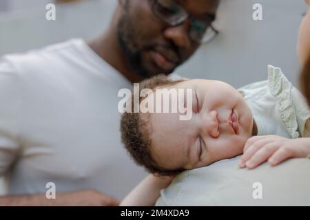 Vater mit süßem Mädchen, das auf Mutter Schulter schläft Stockfoto