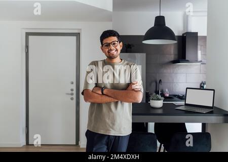 Lächelnder junger Mann mit zu Hause verschränkten Armen Stockfoto