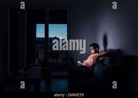 Junger Mann, der zu Hause ein Notebook benutzt Stockfoto