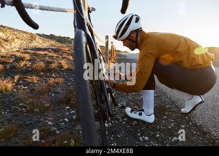 Junger Radfahrer, der eine Befestigungsmutter am Helm trägt Stockfoto