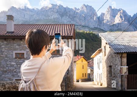 Spanien, Kastilien und Leon, Posada de Valdeon, weibliche Touristen, die Fotos von Steinhäusern in Picos de Europa machen Stockfoto