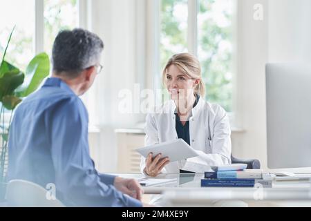 Arztin, die mit der Patientin über Tablet PC in der Praxis berät und diskutiert Stockfoto