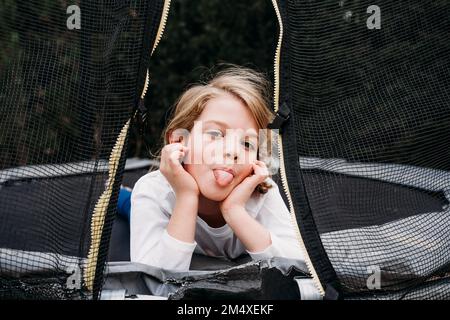 Ein Mädchen, das im Garten auf dem Trampolin liegt Stockfoto