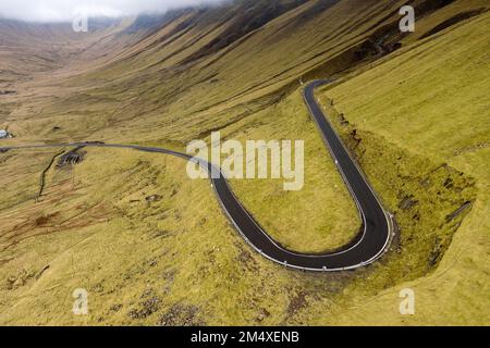 Gekrümmte, leere Straße im Tal an den Bergen Stockfoto