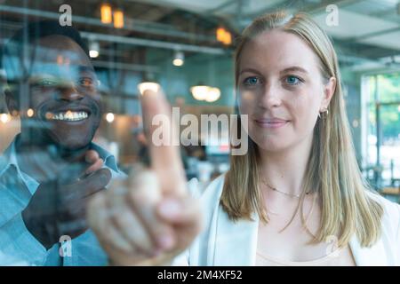 Glücklicher Geschäftsmann mit Geschäftsfrau, die Glas im Café berührt Stockfoto