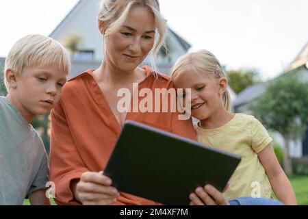 Lächelnde Frau, die Kindern einen Tablet-PC zeigt Stockfoto