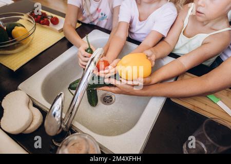 Mutter und Töchter waschen Gemüse in der Küche Stockfoto