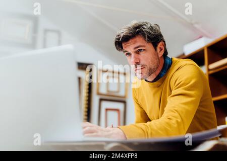 Fokussierter Handwerker mit Laptop in der Werkstatt Stockfoto