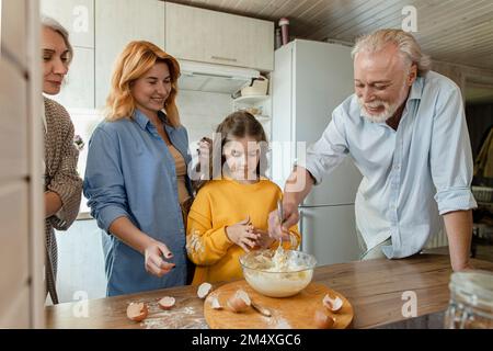 Eine Familie aus drei Generationen bereitet Teig für Brot in der Küche zu Stockfoto