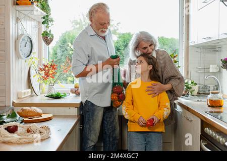 Großeltern und Enkelin packen frische Lebensmittel in der Küche aus Stockfoto