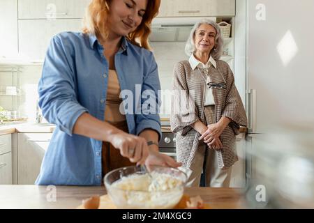 Seniorin und Erwachsene Tochter bereiten Teig für Brot in der Küche zu Stockfoto