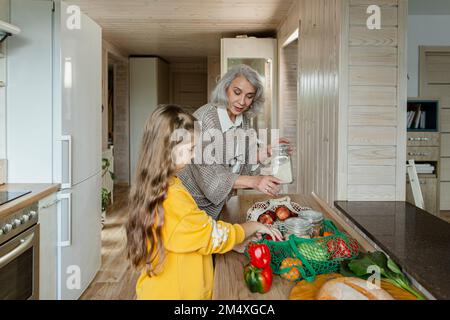 Großmutter und Enkelin packen frische Lebensmittel in der Küche aus Stockfoto