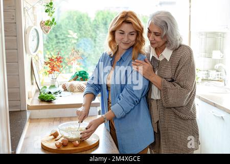 Seniorin und Erwachsene Tochter bereiten Teig für Brot in der Küche zu Stockfoto