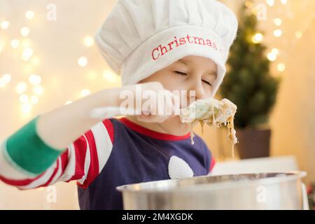 Ein Junge mit geschlossenen Augen, der zu Hause Lebkuchenteig riecht Stockfoto