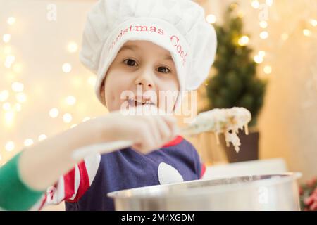 Süßer Junge, der zu Hause Lebkuchenteig zubereitet Stockfoto