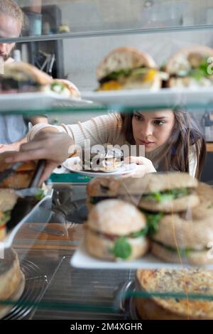 Barista nimmt Burger von der Ausstellungstheke im Café mit Stockfoto