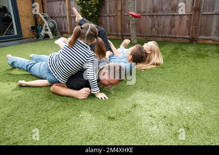 Verspielter Mann, der seine Freizeit mit Kindern im Garten verbringt Stockfoto