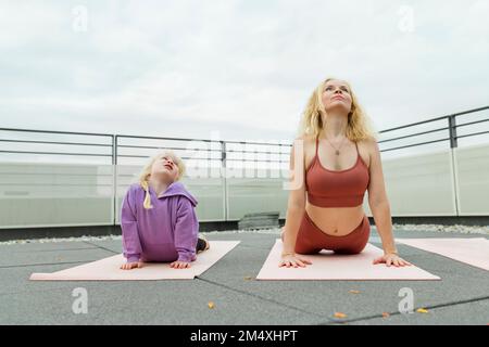 Mutter und Tochter üben gemeinsam Yoga auf der Terrasse Stockfoto