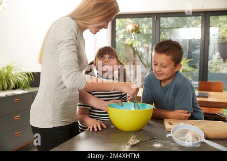 Mädchen und Bruder helfen Schwester bei der Zubereitung von Keksen zu Hause Stockfoto