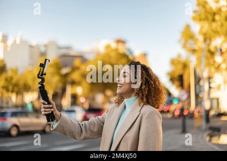 Glückliche junge Frau, die mit dem Smartphone auf dem Stativ filmt Stockfoto
