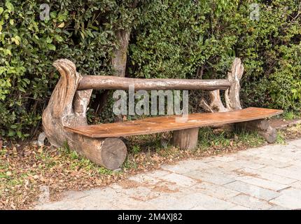 Handgefertigte Holzbänke im Park, umgeben von grünen Büschen. Stockfoto