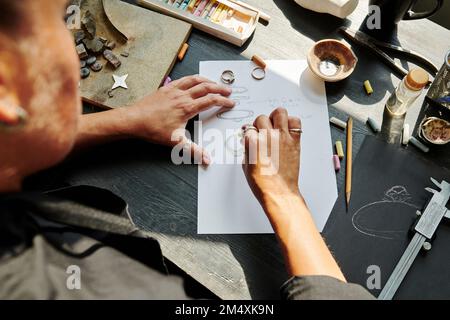 Juwelier skizziert Ringdesign auf Papier auf der Werkbank Stockfoto