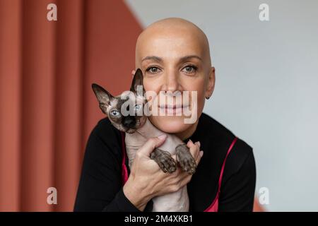 Kahlköpfige Frau, die die haarlose Sphynx-Katze umarmt Stockfoto