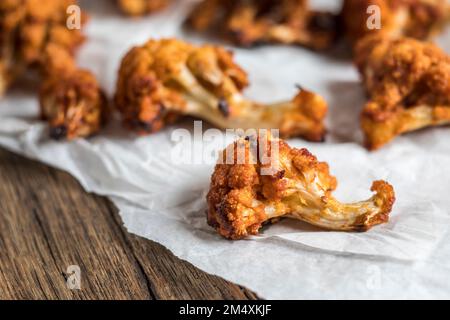 Gegrillter Blumenkohl auf Wachspapier über Schneidebrett Stockfoto