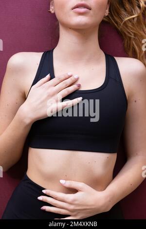 Junge Frau, die zu Hause auf einer Trainingsmatte liegt Stockfoto