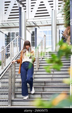 Frau, die ein Smartphone benutzt und die Treppe runterfährt Stockfoto