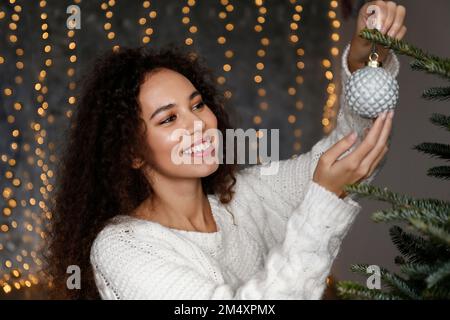 Glückliche, schöne Frau, die zu Hause den Weihnachtsbaum schmückt Stockfoto