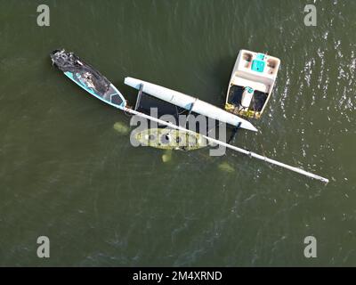 Aus der Vogelperspektive blickt man direkt von oben auf gekenterte Boote, die in einem Feuer verbrannt wurden Stockfoto