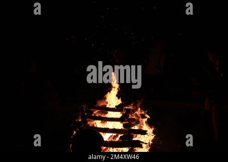 Ein Blick auf brennende Holzstämme Lagerfeuer, die nachts übereinander gestapelt sind Stockfoto