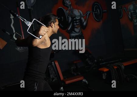 Ein südasiatischer Mann, der Bizeps im Fitnessstudio macht Stockfoto