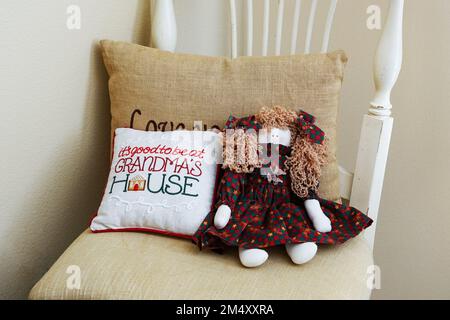 Gemütlicher Stuhl mit einladendem Kissen und Puppe im Grandmas House Stockfoto