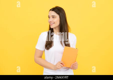 Studentin hält Bücher isoliert auf gelbem Hintergrund im Studio. Englische Sprachschule, Bildungskonzept. Stockfoto