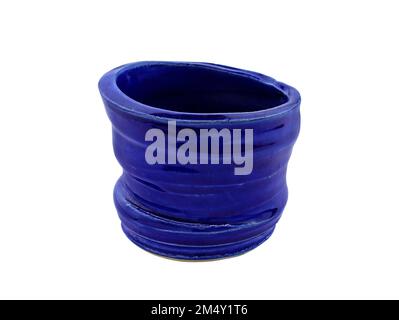 Dunkelblaue Keramikbecher isolieren. Glänzende, dekorative Nahaufnahme aus Glas. Topf mit gezackten Kanten aus blau-glasiertem Ton. Stockfoto