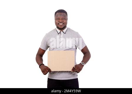 Porträt eines gutaussehenden jungen Mannes, der ein Stück Pappe zeigt, während er in die Kamera lächelt. Stockfoto