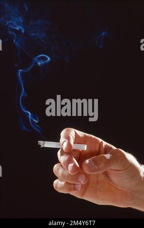 Die Nahaufnahme einer Hand, die eine Zigarette in der Hand hält, geht in die Luft Stockfoto