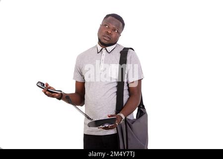 Porträt eines gutaussehenden jungen Mannes, der denkt, während er ein Handy hält. Stockfoto