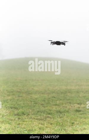 Eine vertikale Aufnahme einer DJI Mavic Air Drohne, die in der Luft umringt vom Nebel fliegt Stockfoto