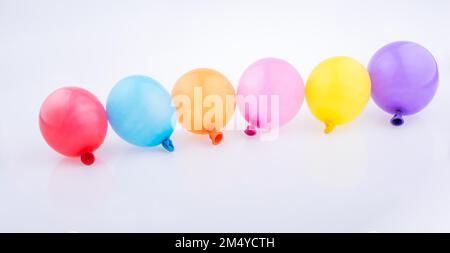 Bunte kleine Luftballons in Linie auf weißem Hintergrund Stockfoto