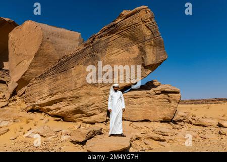 Ein Mann zeigt auf Felsschnitzereien, UNESCO-Stätte Bir Hima Rock Petroglyphen und Inschriften, Najran, Königreich Saudi-Arabien Stockfoto