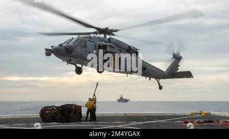 PAZIFIK (17. DEZEMBER 2022) – USA Navy-Matrosen, die der Amphibien-Transportladerampe USS Anchorage (LPD 23) zugeteilt sind, bereiten sich darauf vor, Vorräte in die USA zu bringen Navy MH-60s Seahawk während einer Nachlieferung auf See, Dezember 17. Der 13. MEU ist eine Kraft der Bereitschaft, die darauf ausgerichtet ist, in allen Bereichen rasch auf Krisen zu reagieren. Die 13. Marineexpeditionstruppe wird auf die Makin Island Amphibious Ready Group aufgeladen, die aus dem Amphibienschiff USS Makin Island (LHD 8) und den Amphibienschiffen USS John P. Murtha (LPD 26) und dem Anchorage besteht. Und im US-Flottenbereich 7. tätig sind, um die inte zu verbessern Stockfoto