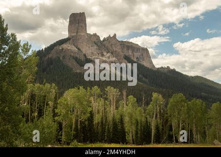 Chimney Rock und Courthouse Mountain am Owl Creek Pass, der hinter einem Hain aus gemischten Aspens und immergrünen in der Nähe des Silver Jack Reservoir, Colorado, zu sehen ist. Stockfoto