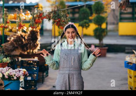 Verspielte Bauernfrau in Jeansanzug, die beim posieren aufrichtig lächelt. Der Begriff der Landwirtschaft. Stockfoto