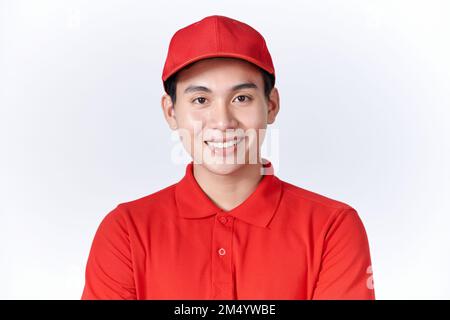 Fröhlicher asiatischer Kurier in Uniform, rote Mütze und T-Shirt Stockfoto