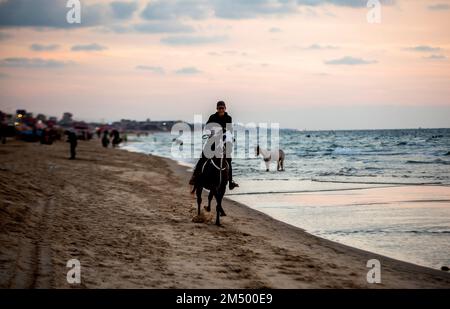 Gaza, Palästina. 24. Dezember 2022. Ein Palästinenser reitet sein Pferd am Ufer des Mittelmeers in Gaza City. Kredit: SOPA Images Limited/Alamy Live News Stockfoto